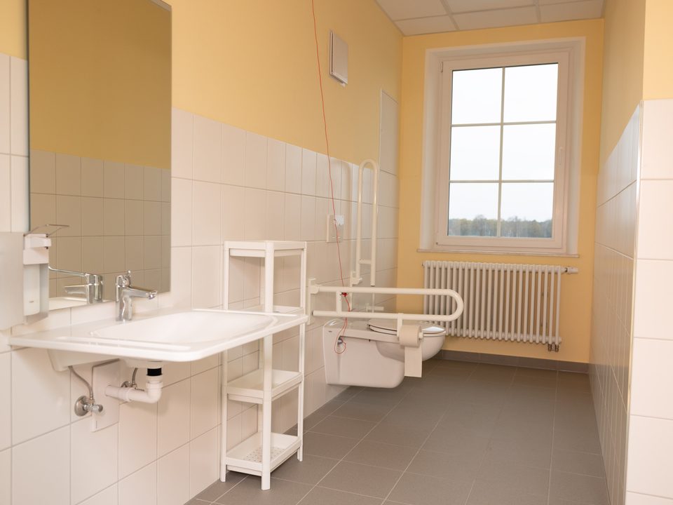 Behindertengerechtes Bad mit unterfahrbarem Waschbecken und Haltegriffen am WC