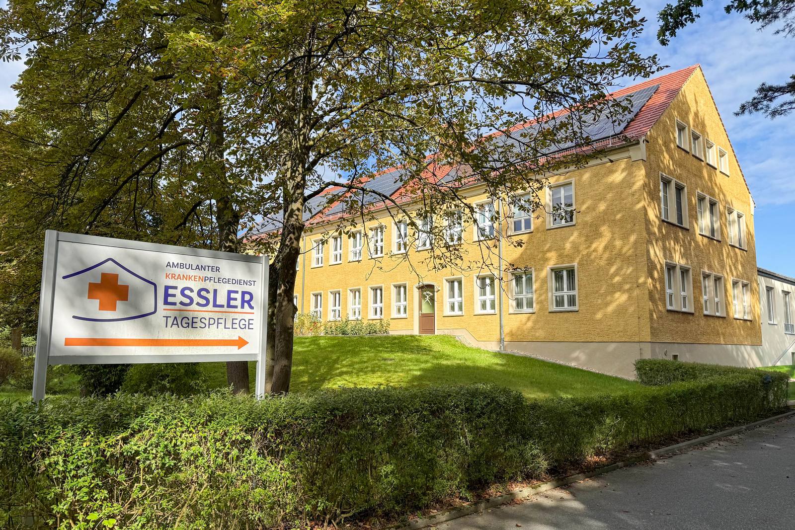 Das gelbe, sanierte Gebäude der Tagespflege Essler in Dauban mit Hinweisschild im Vordergrund