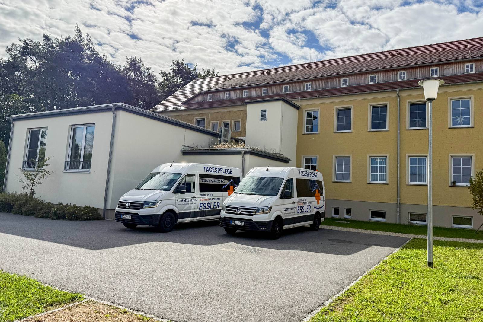 Zwei weiße Kleinbusse mit der Aufschrift Tagespflege Essler vor dem Haus in Dauban